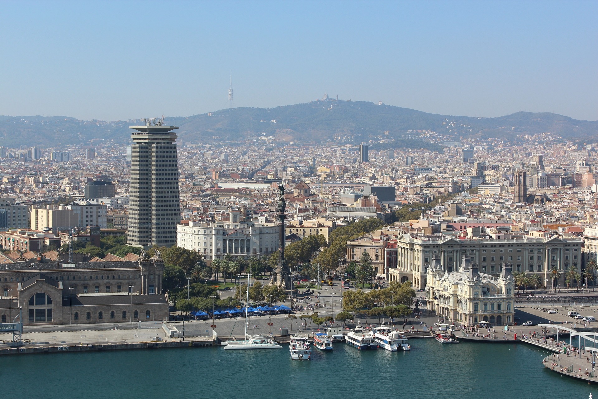 the port in barcelona, a few boats alongside the docks, the city visible behind.